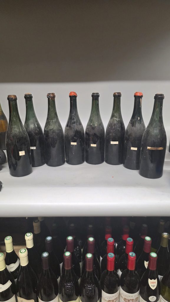 Bouteilles de vin anciennes alignées dans une cave lors d’une estimation de collection de vins